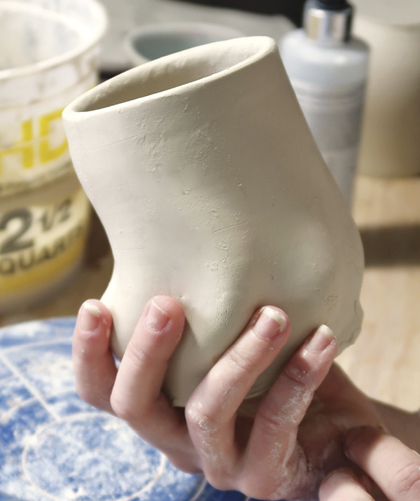 4 Use damp fingers to apply pressure along the inner wall, pushing out while sliding fingers up toward the rim until the wall of the mug begins to swell.