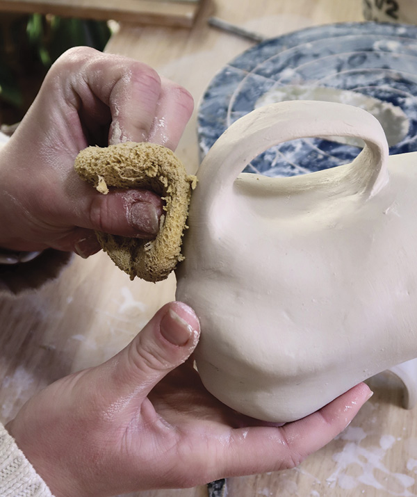 11 Attach together and thoroughly blend the clay from the handle into the exterior of the piece, using a sponge to smooth the connection.
